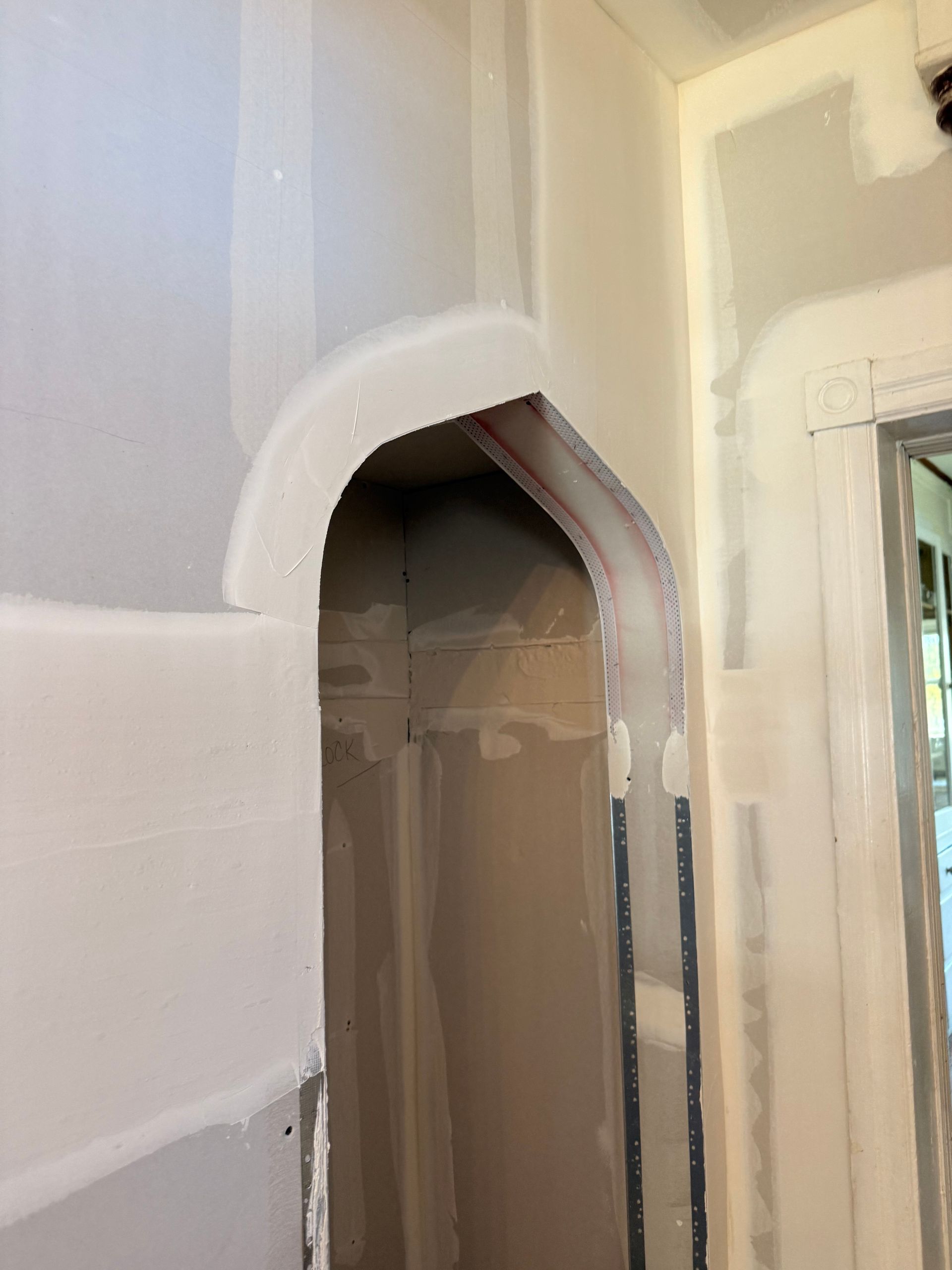 Drywall archway in a newly constructed room, interior view.