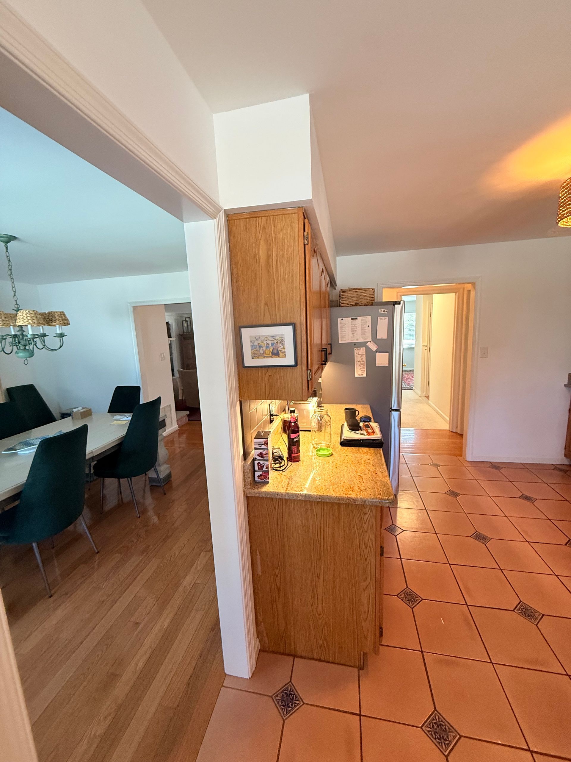 Kitchen with wood cabinets, tiled floor, refrigerator, and dining area visible.