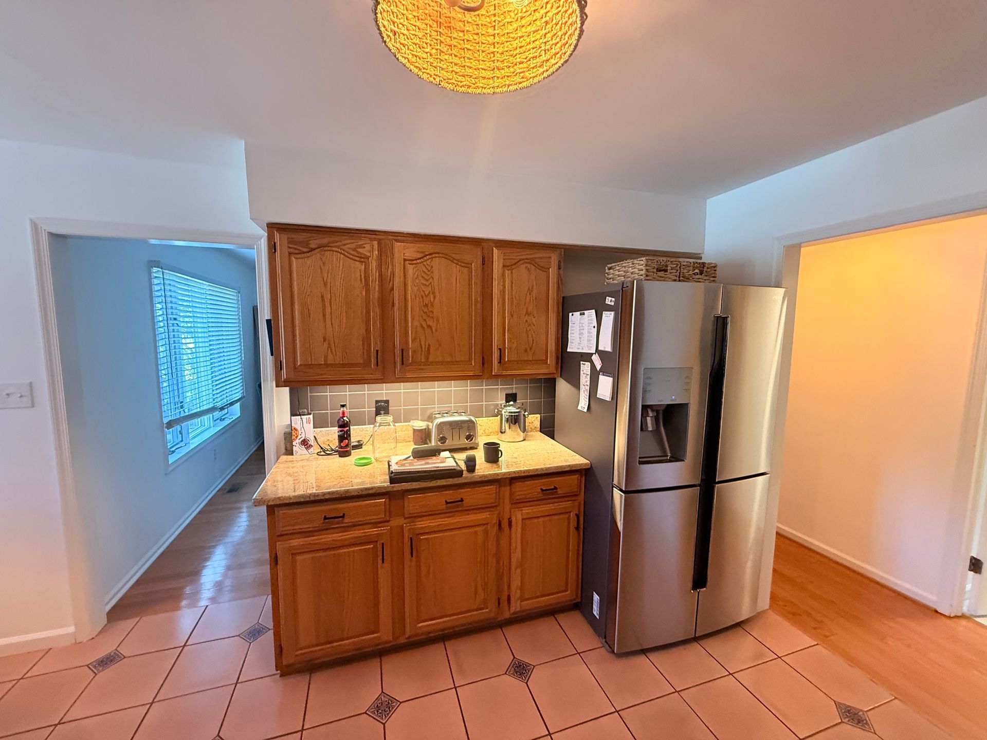 Kitchen with wooden cabinets, stainless steel refrigerator, and tile floor.