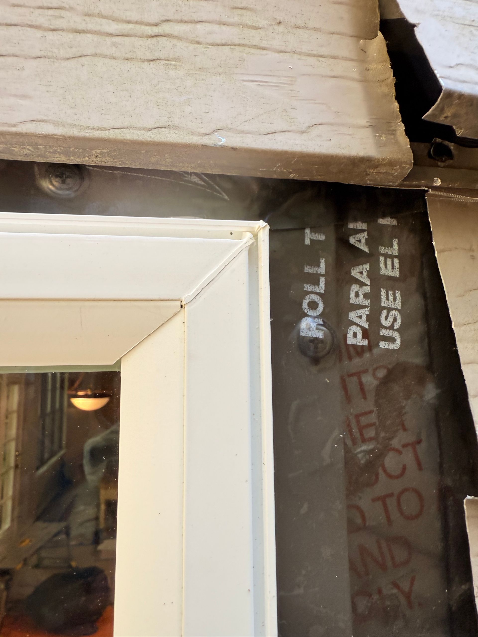 Close-up of a white window frame installed against a dark, textured wall, with visible sealant and exterior building material.
