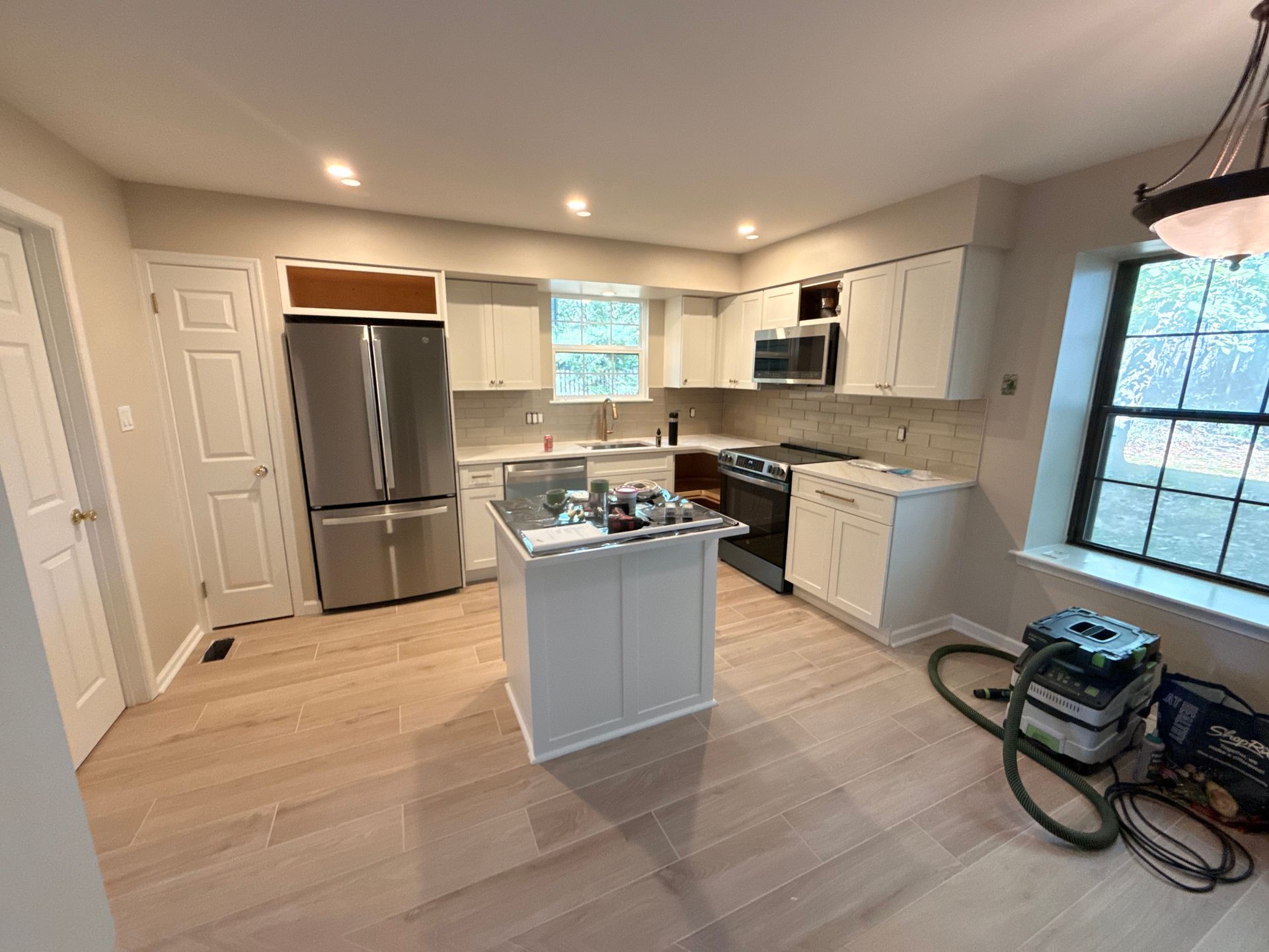 Newly renovated kitchen with white cabinets, stainless steel appliances, and wood flooring.
