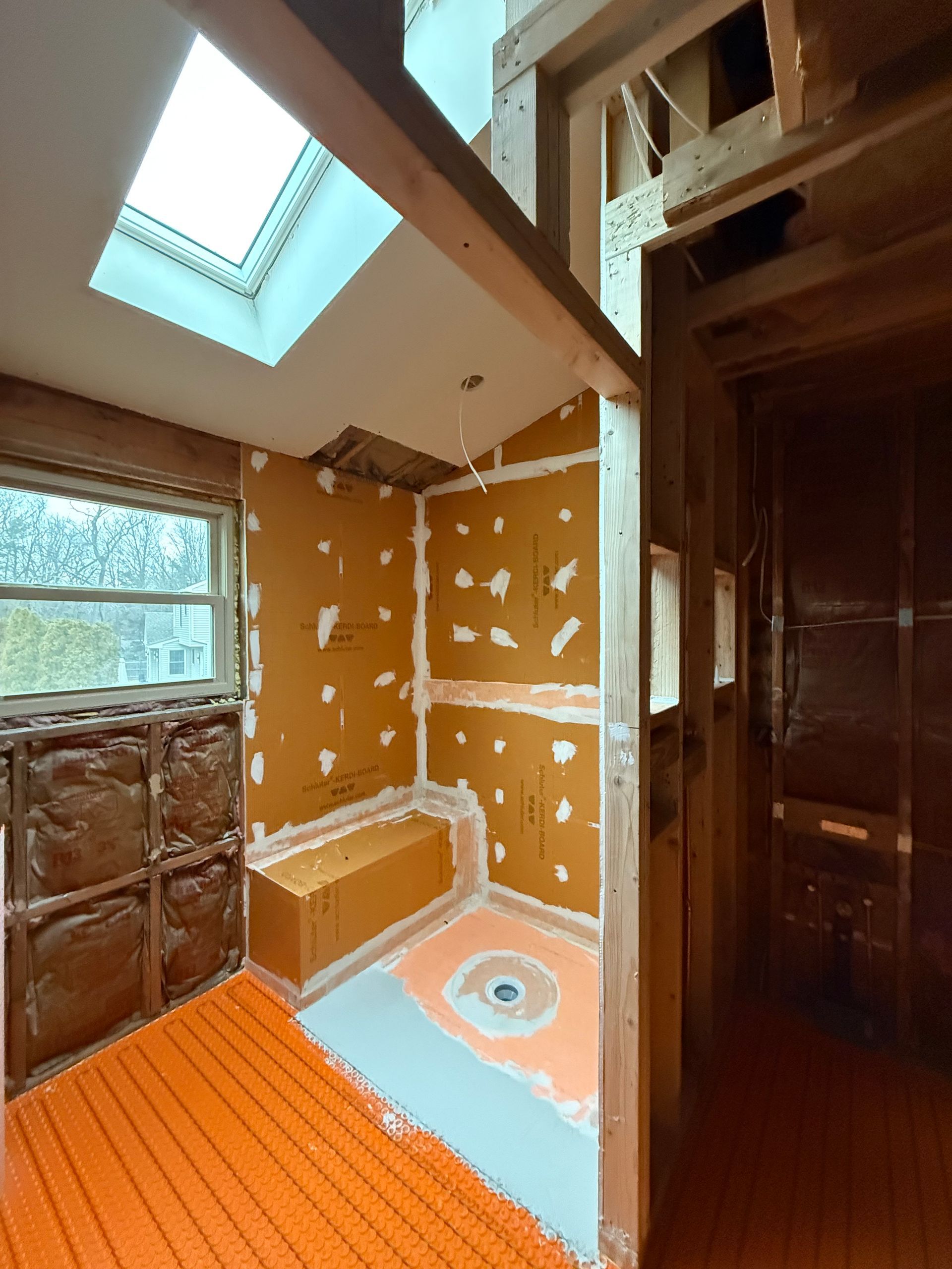 Bathroom remodel in progress: orange tile backing, shower seat, floor heating, skylight.