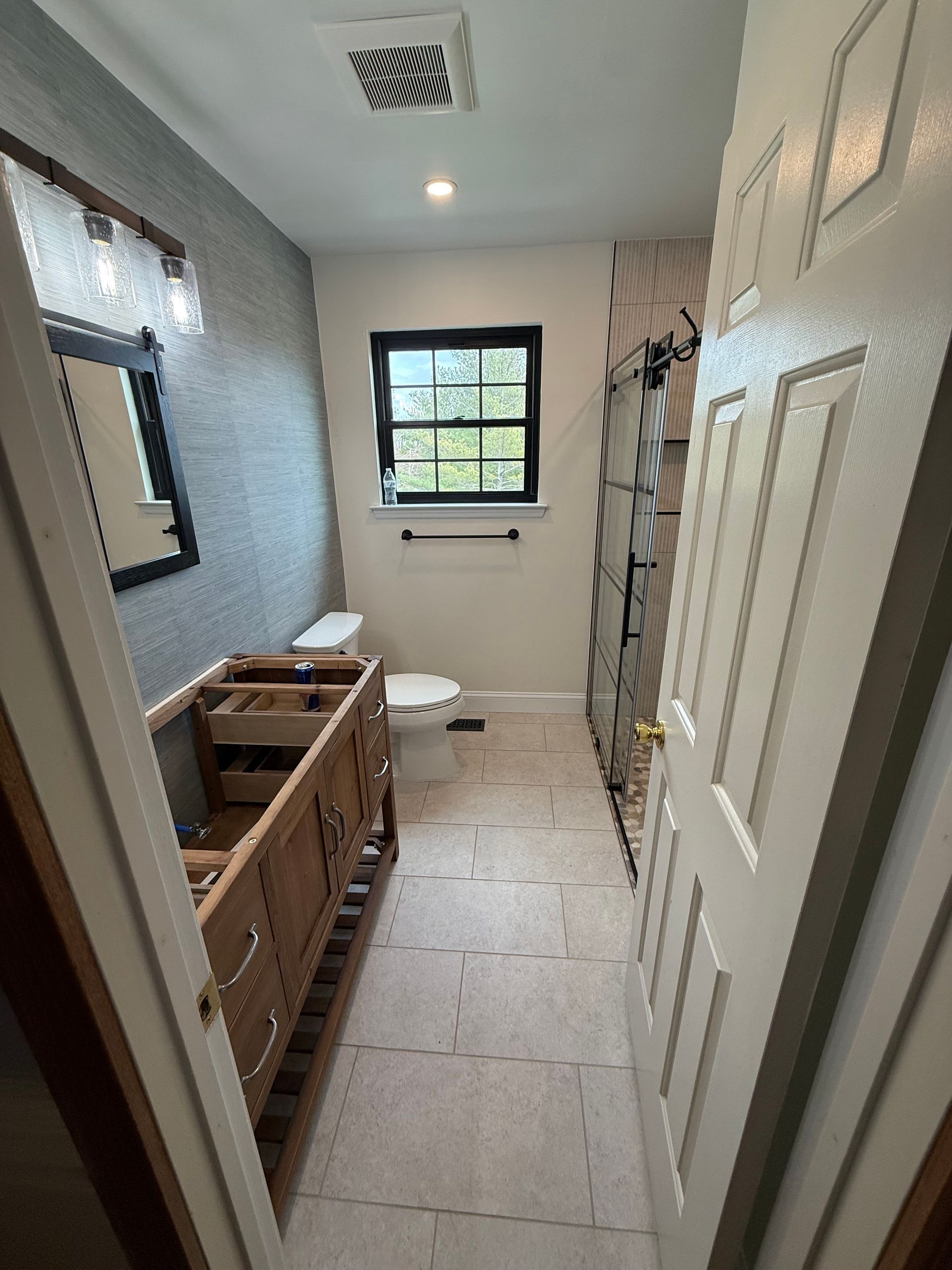 Bathroom with vanity, toilet, window, and new flooring, neutral colors.