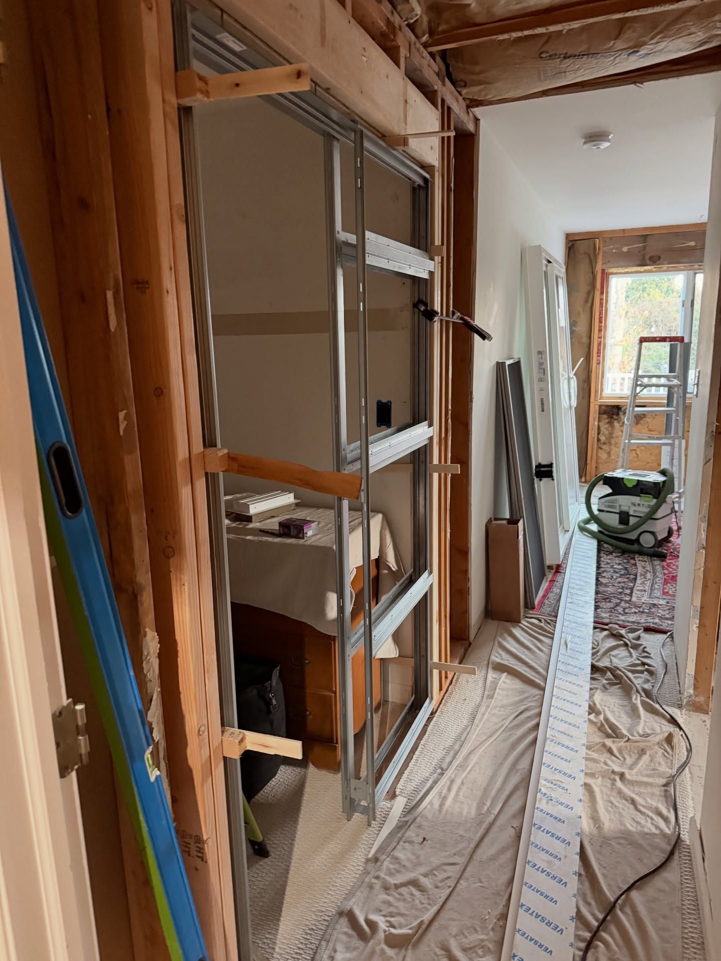 Interior construction in progress, hallway with exposed framing and metal door frame.