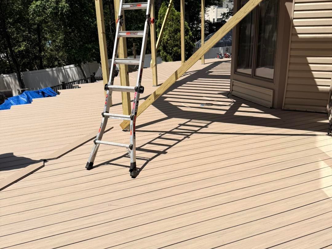 Light brown deck with a ladder, wooden support beams, and a house.