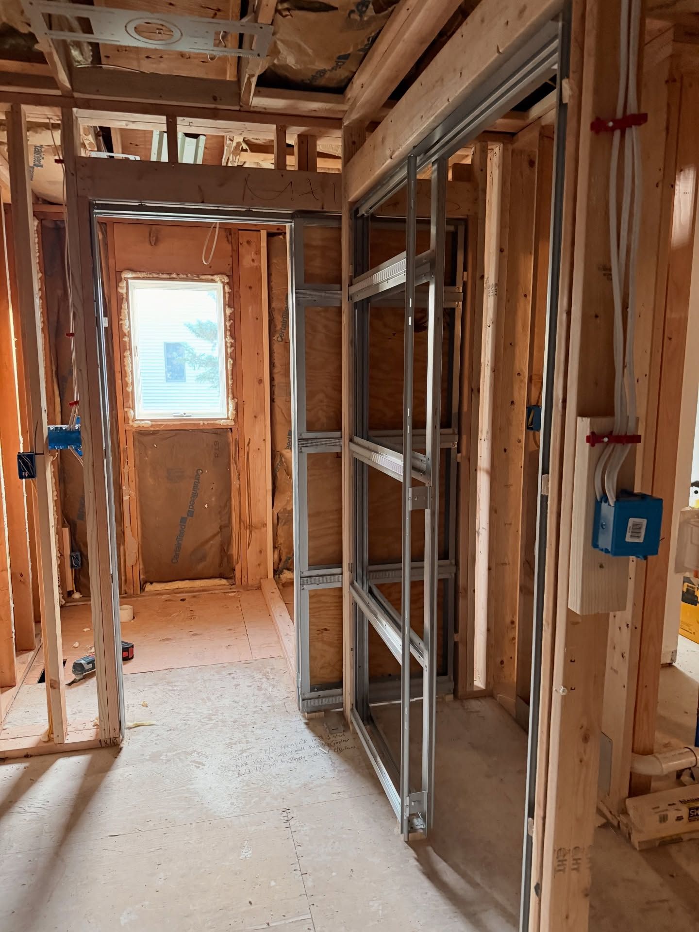 Interior view of a building under construction.  Wooden studs and metal framing for a doorway and closet, wiring visible.