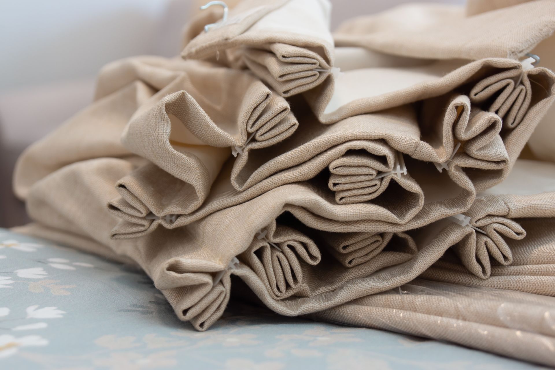 Stacked beige folded fabric with rolled edges on a soft surface