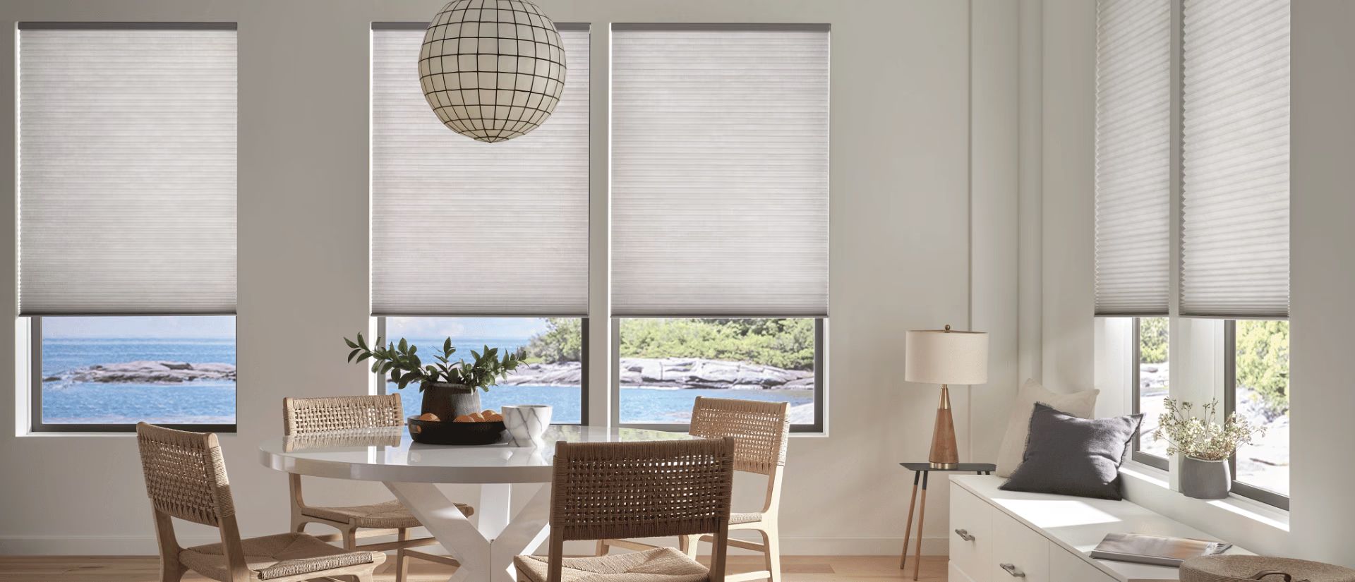 Bright dining room with large windows, woven chairs, and a table overlooking the water