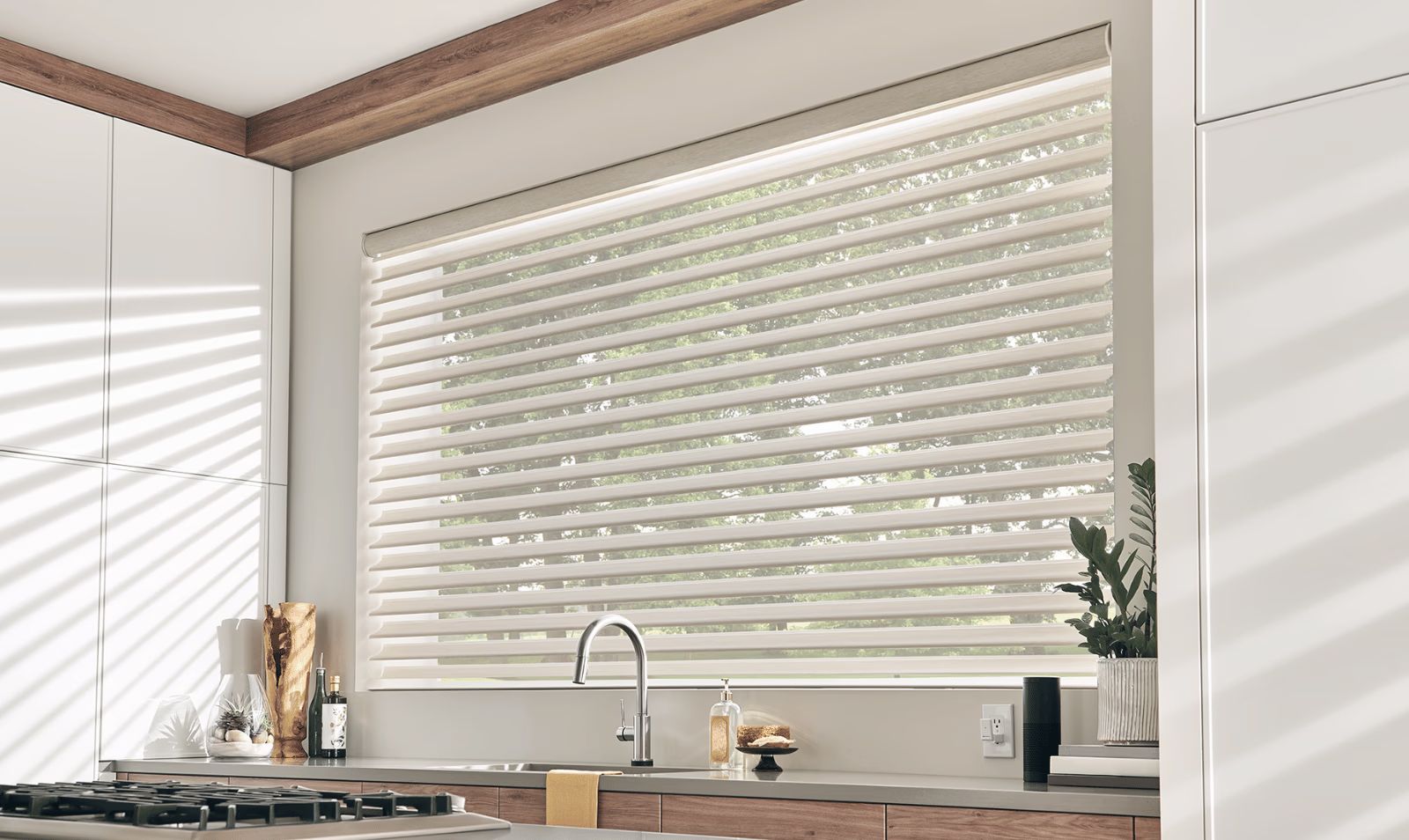 Bright kitchen with large window, white blinds, and a sink under natural light.