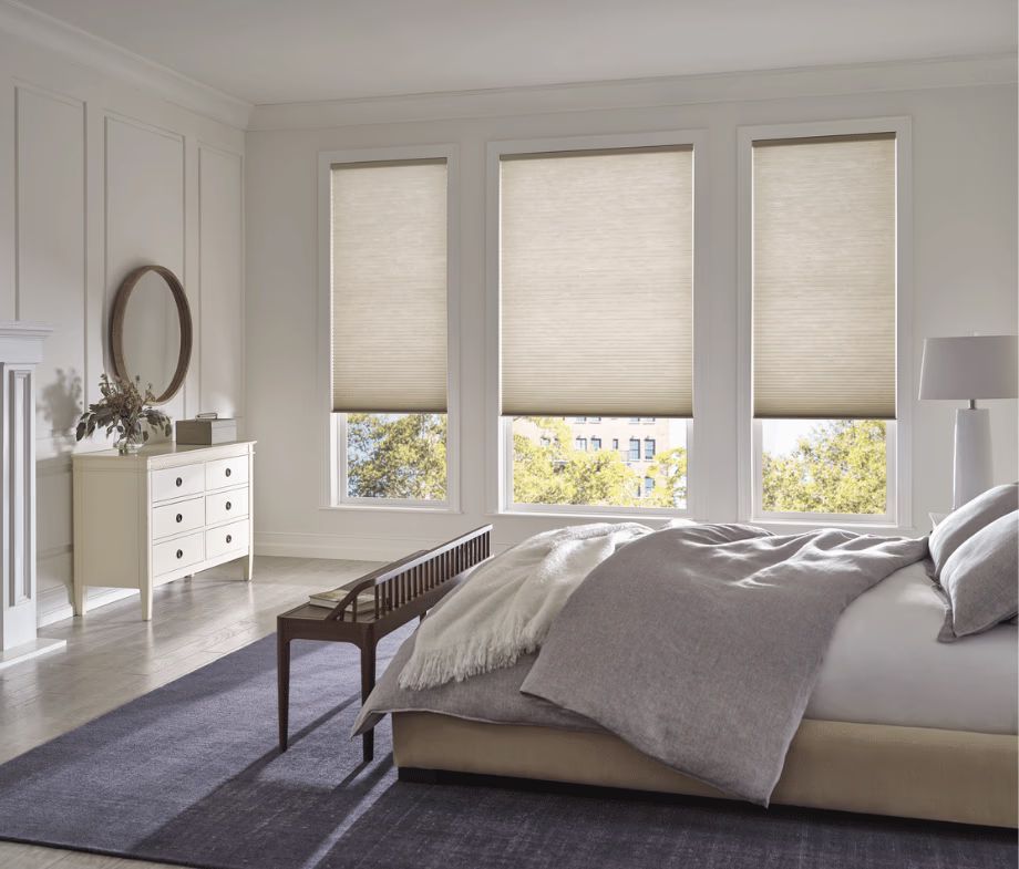 Bright minimalist bedroom with large windows, white decor, and a gray bedspread