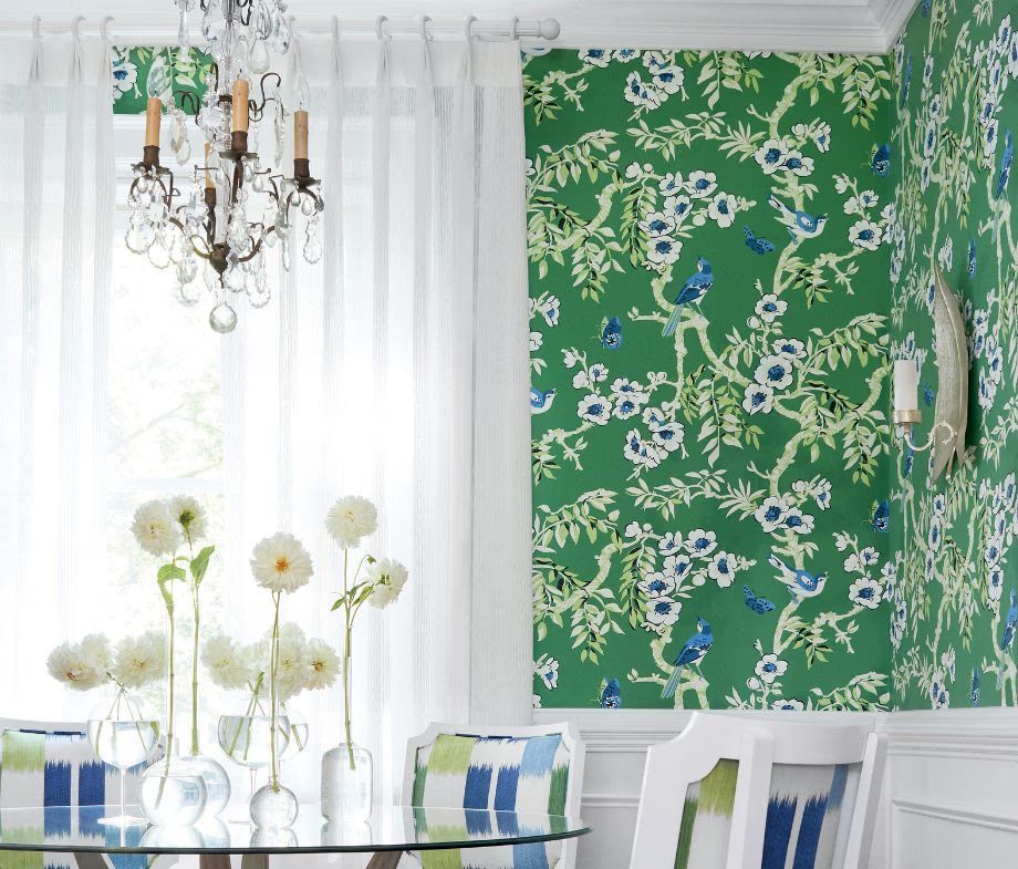 Bright dining room with green floral wallpaper, white curtains, chandelier, and blue-striped chairs around a table