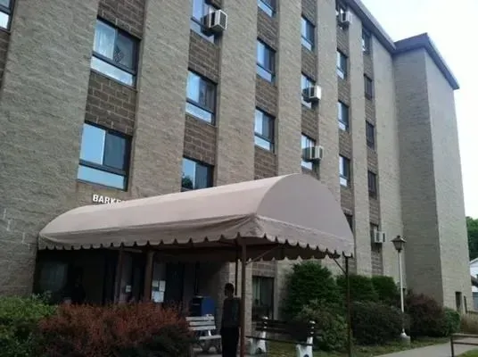 A low-angle view of a multi-story brick residential building with a beige canopy over the main entrance.