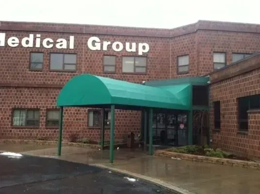 A two-story red brick building with a large green awning over the entrance and signage reading 