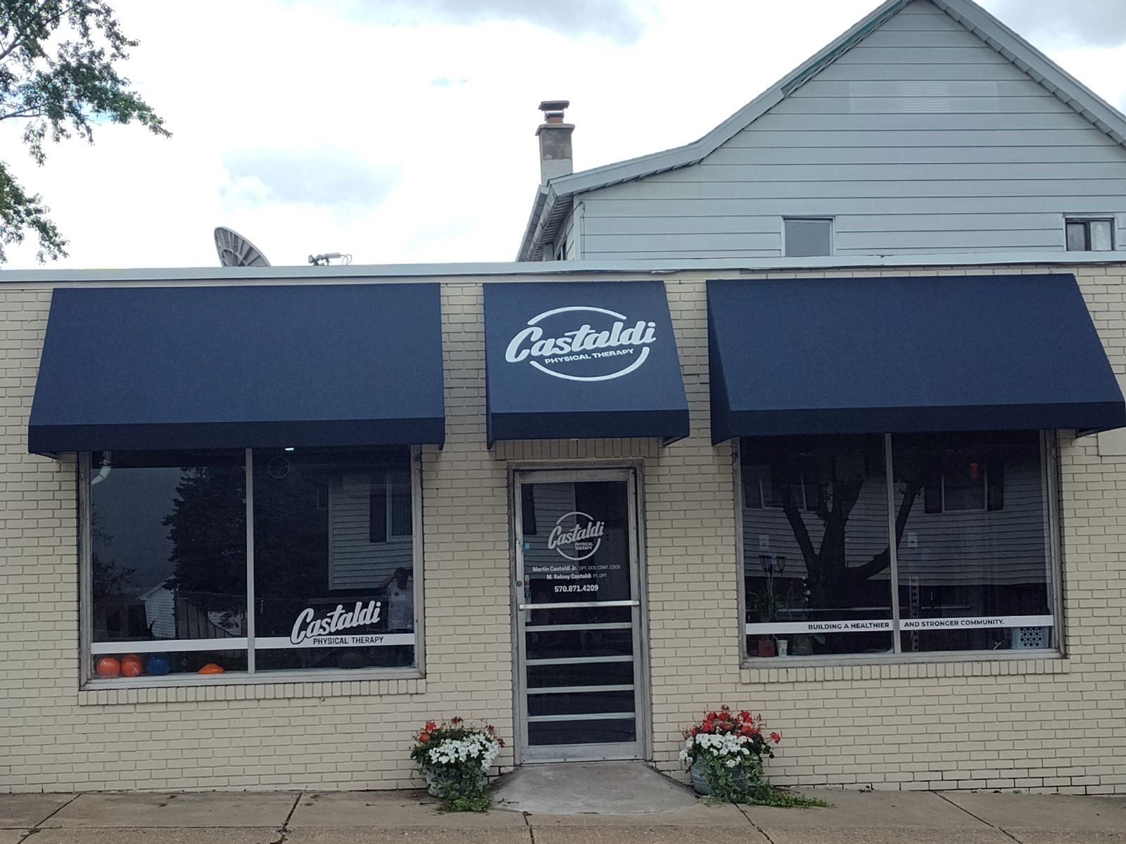 A one-story brick building with three navy blue awnings over the entrance and windows, featuring Castaldi branding.