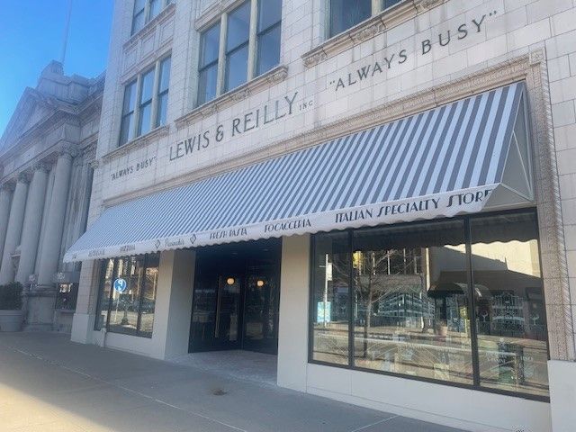 The historic Lewis & Reilly storefront features a blue and white striped awning and large display windows on a city street.