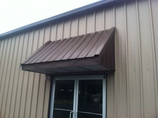 Brown metal awning over a double-door entrance on a beige metal-sided building.