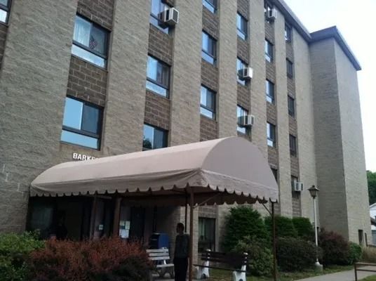 Multi-story brick building with tan awning over entrance, person standing near.
