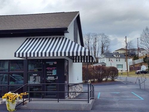 Empty commercial storefront with blue awnings and large windows.