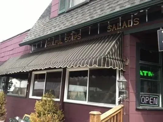 A brown building with a striped awning, a sign reading 