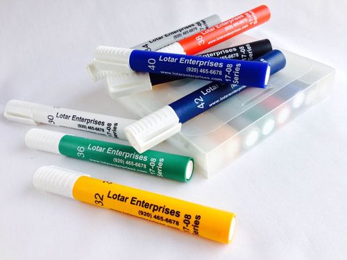 Assorted colorful Lipa Enterprises lip balm tubes stacked on a clear plastic case