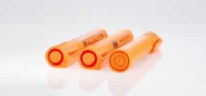 Three orange pen tubes with circular ends on a white background