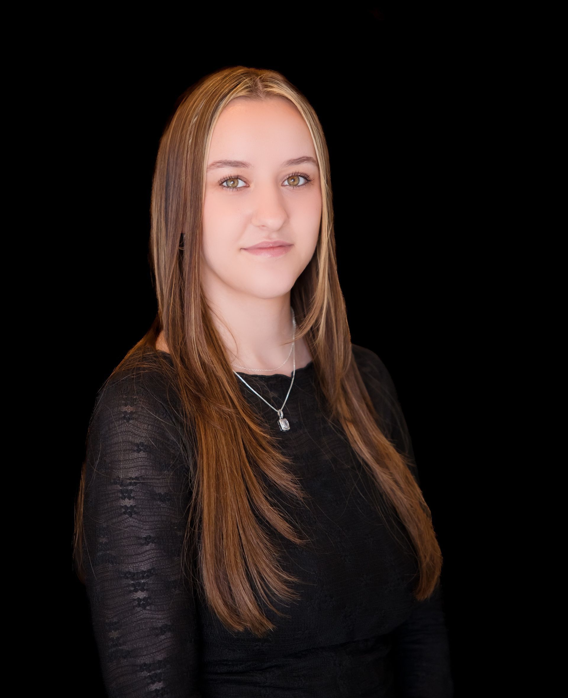 Portrait of a person with long hair wearing a black top against a black background