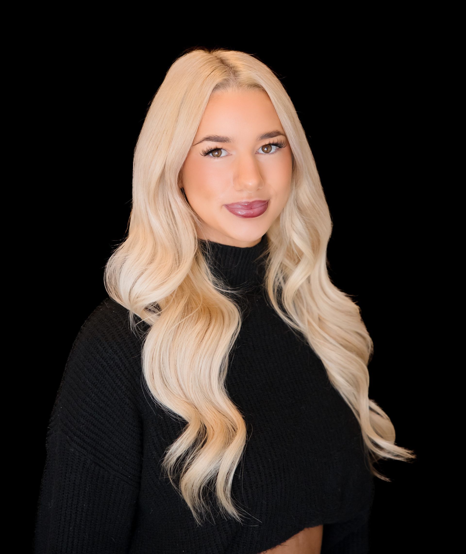 Portrait of a blonde woman in a black turtleneck against a black background