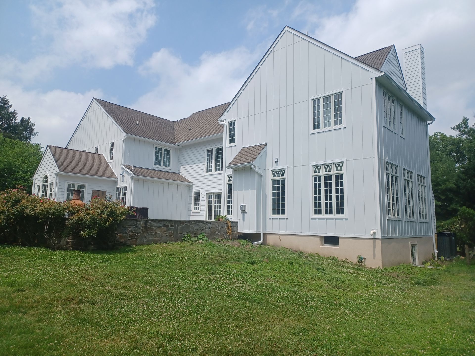 White house with brown roof, set on a grassy hill under a blue sky.