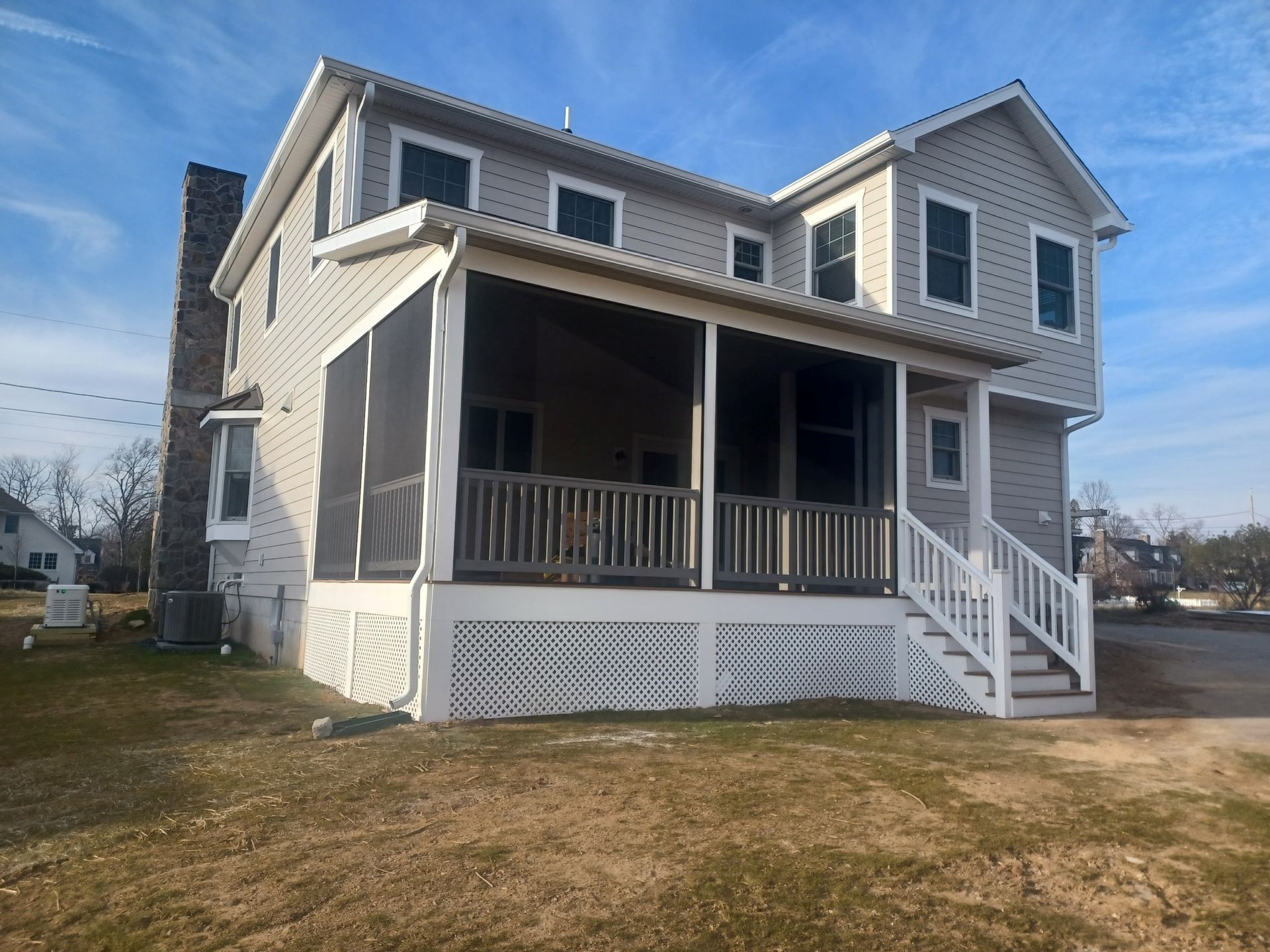 Two-story house with a screened-in porch, white trim, and light gray siding against a blue sky.