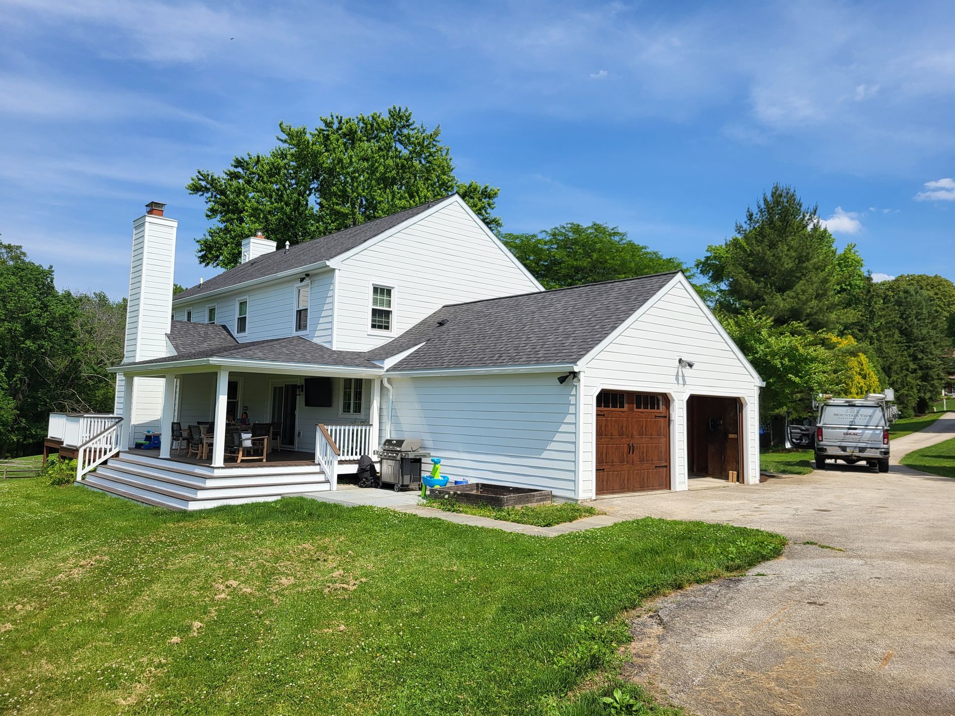 A white house with a garage and a car parked in front of it.