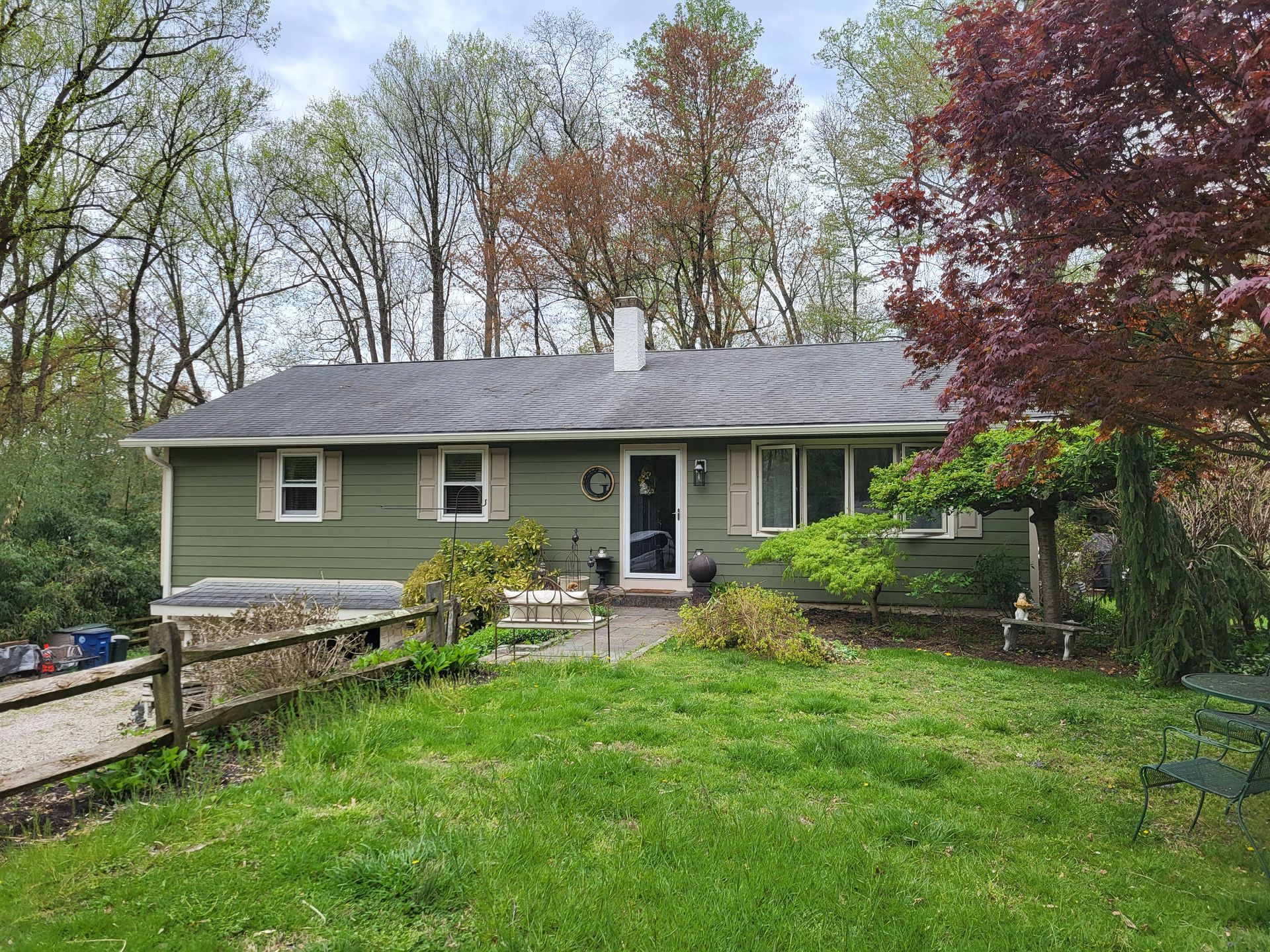 A green house with a fence in front of it and trees in the background