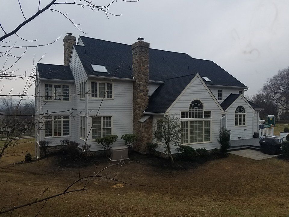 Large white house with a dark roof, two brick chimneys, and multiple windows.