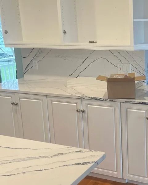 White kitchen with quartz countertops and cabinets, a box on the counter.