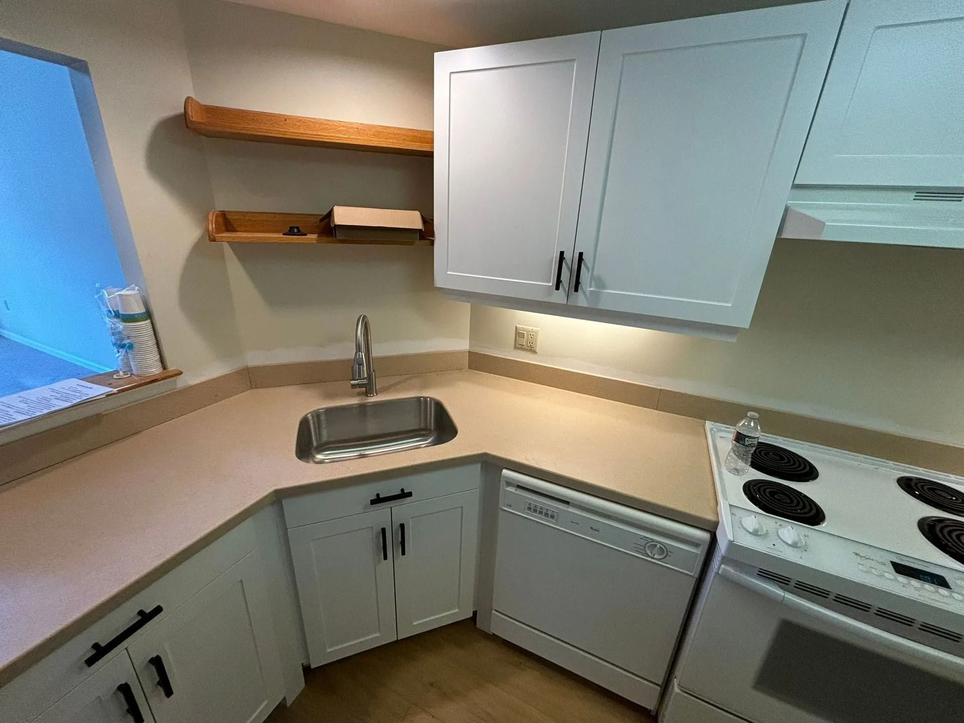 Small kitchen with white cabinets, stainless steel sink, and a stove.