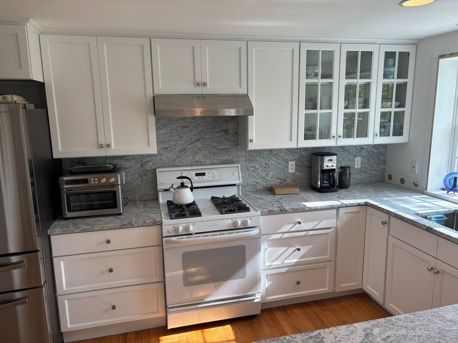 White kitchen with granite countertops, white cabinets, and stainless steel appliances.