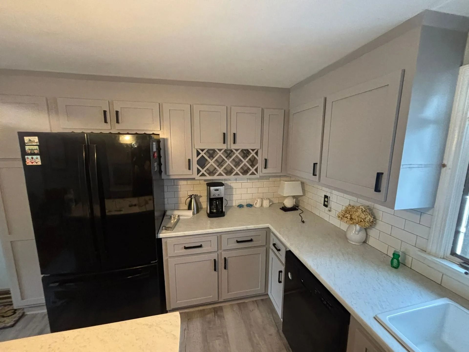Gray kitchen cabinets, black appliances, white countertops, and subway tile backsplash.
