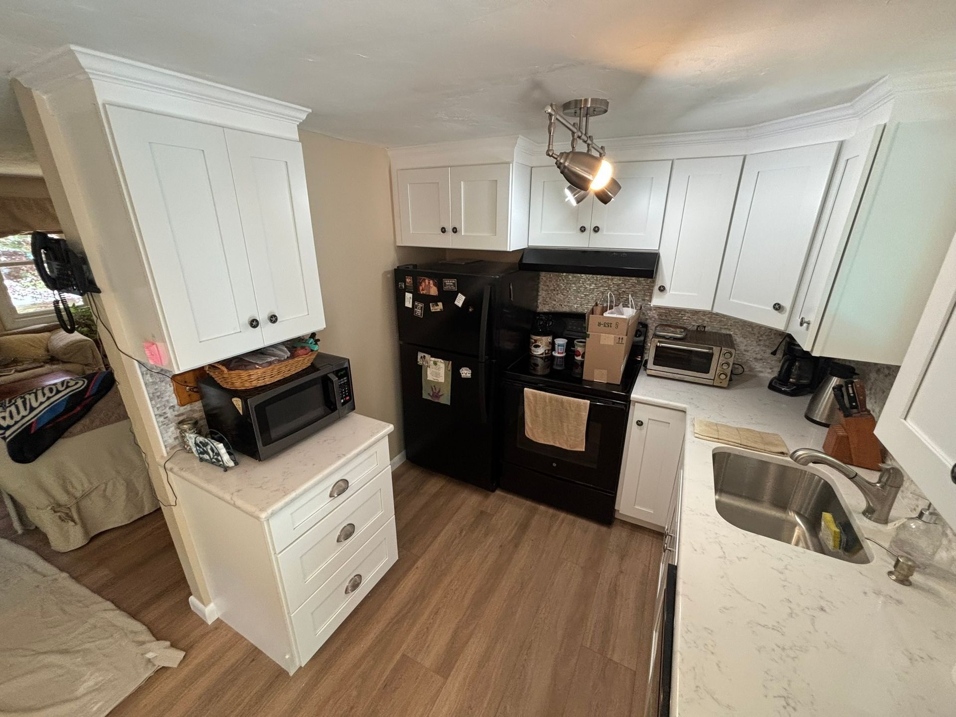 Kitchen with white cabinets, black appliances, and a microwave on a countertop.