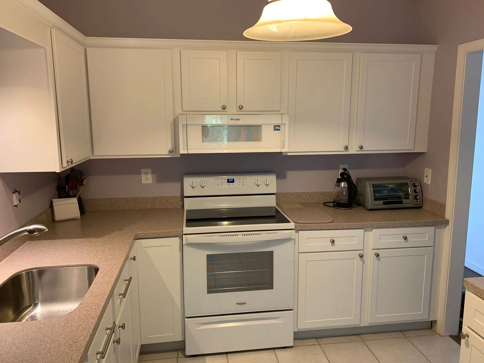 White kitchen cabinets and appliances with a sink, stove, and microwave.