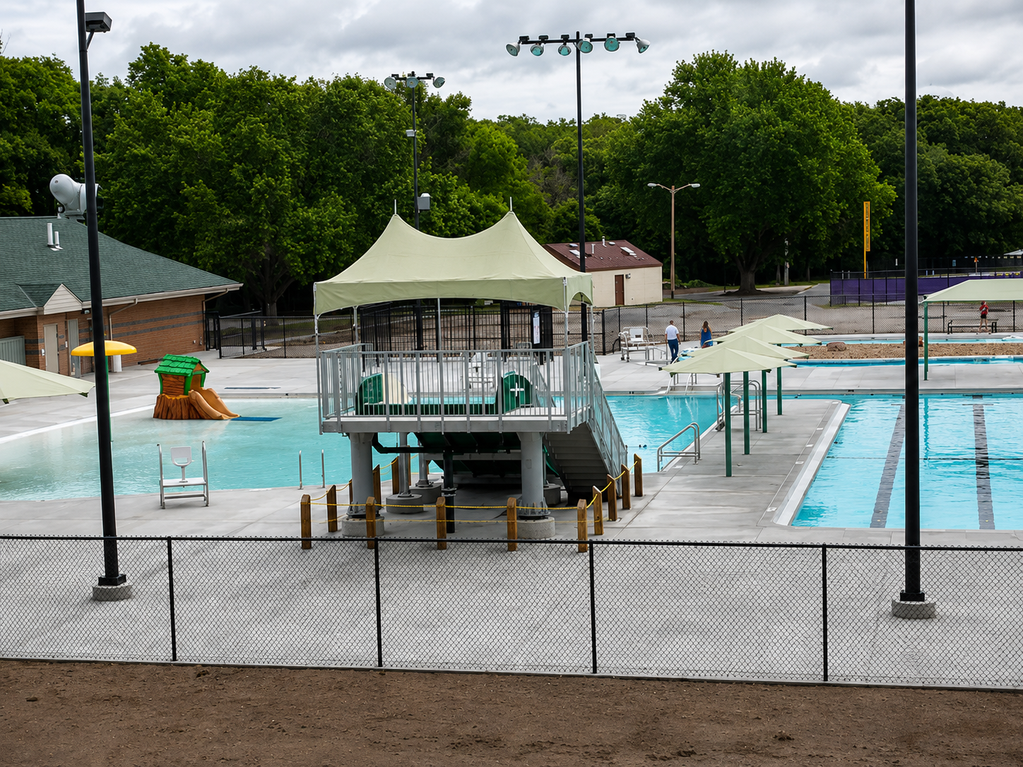 Public swimming pool with a diving platform, water slides, and shade structures.