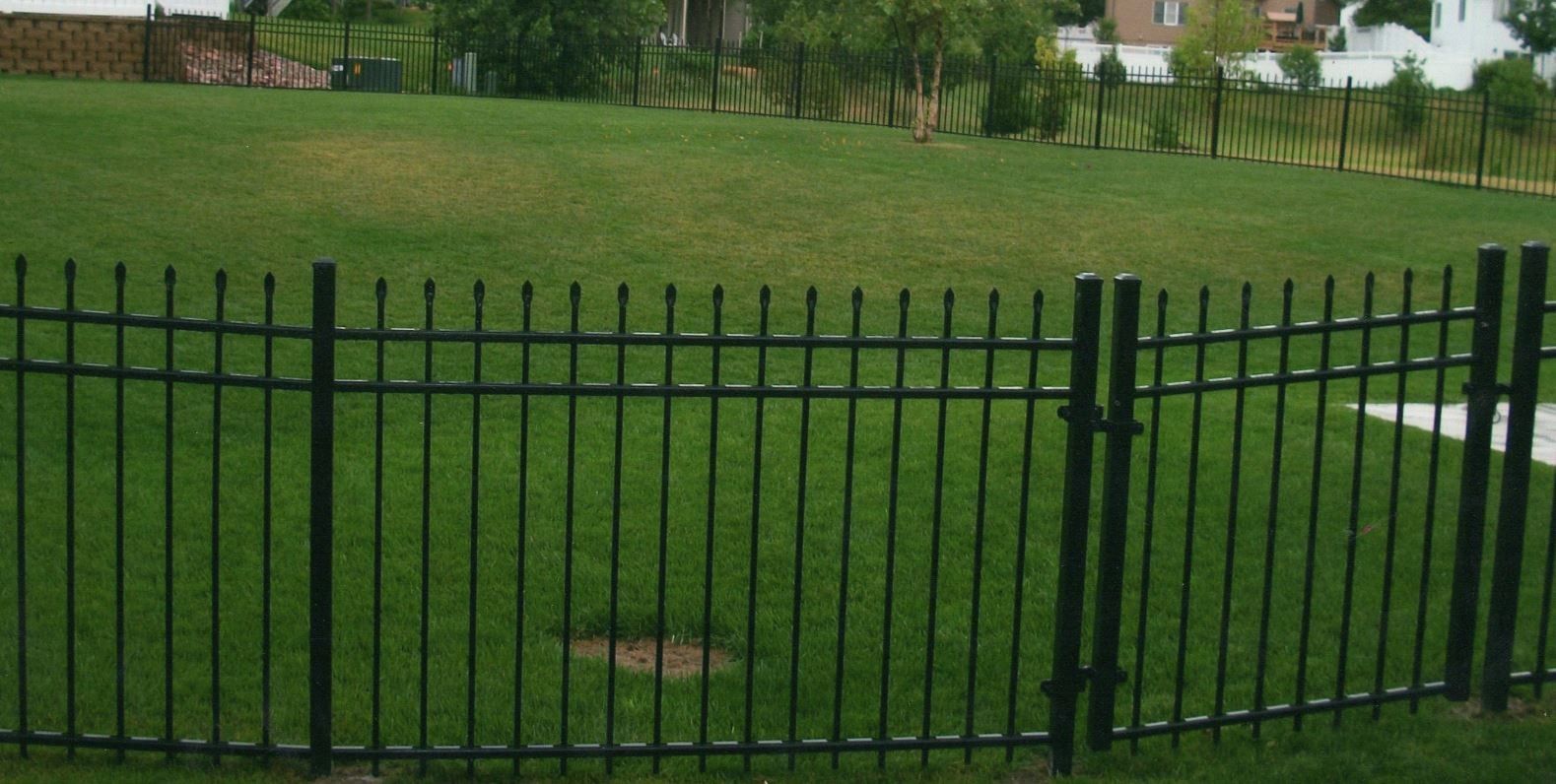 Black metal fence enclosing a green grassy yard.
