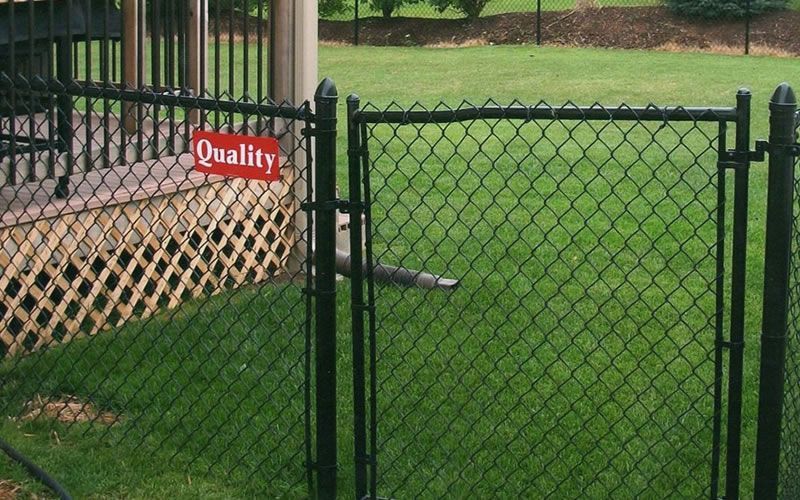 Black chain-link fence and gate in a yard with a red 