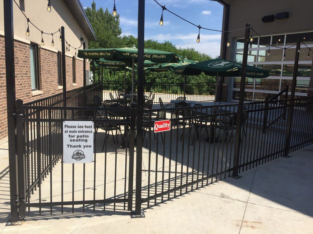 Outdoor patio with tables, umbrellas, and a black fence.