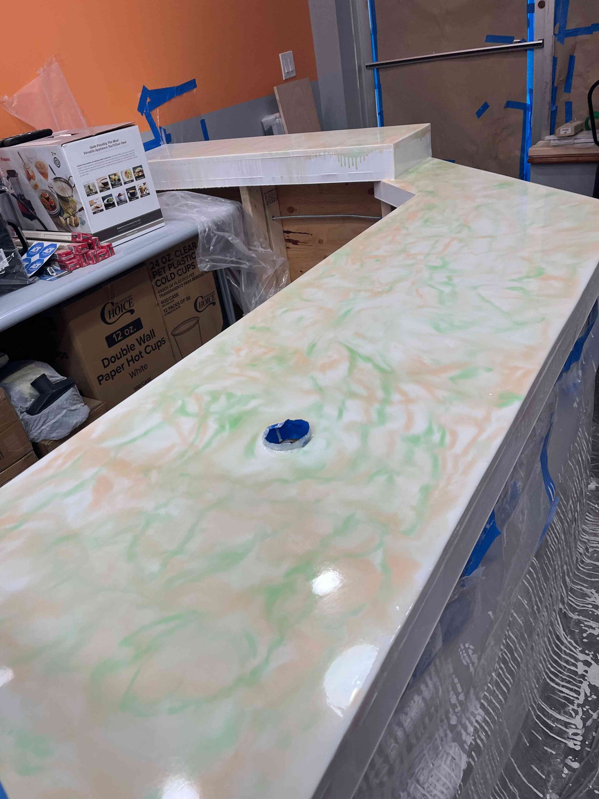 L-shaped countertop with green and tan swirls. A small blue object sits on the surface; bright setting.