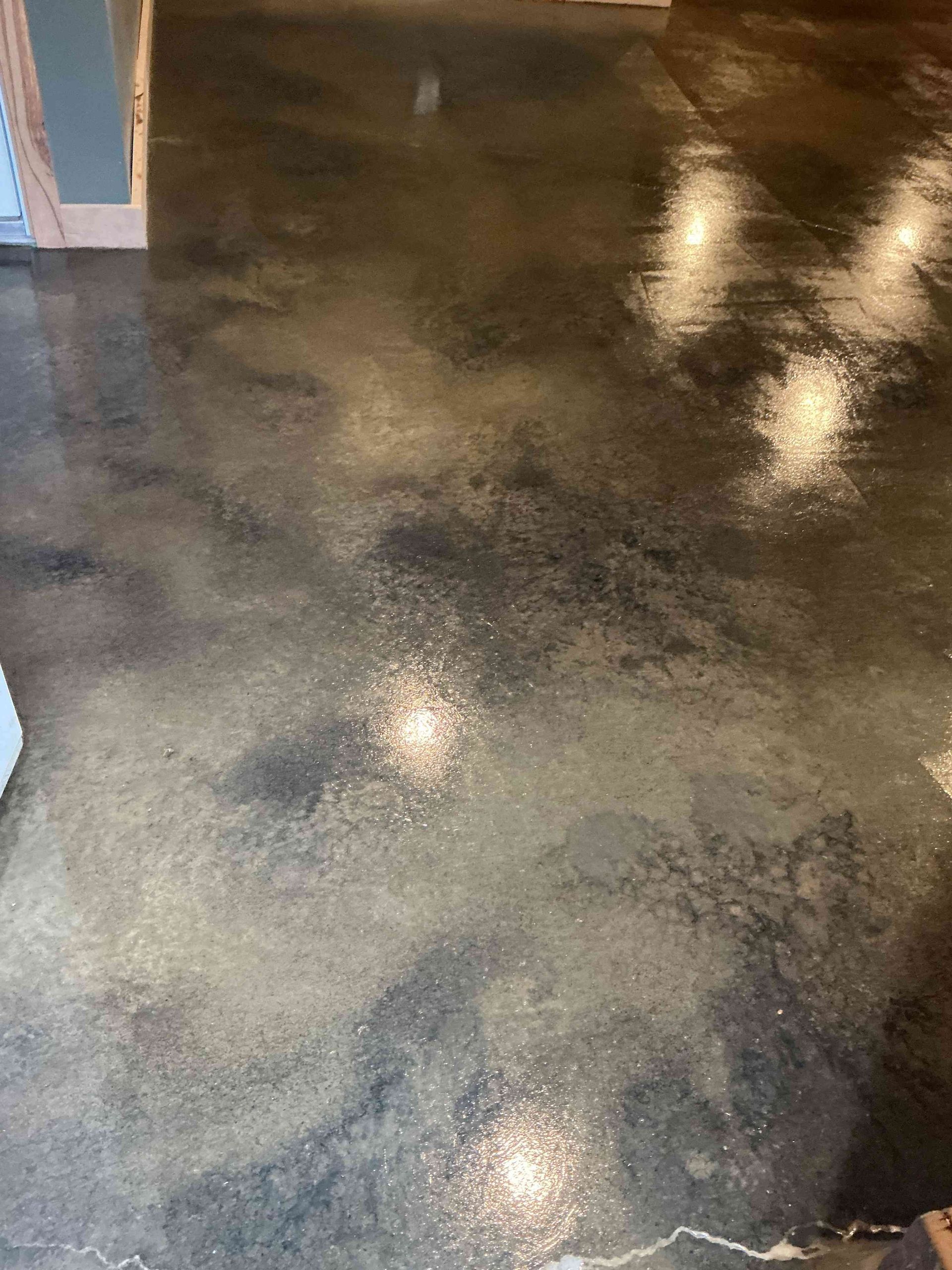 Polished concrete floor with gray and black hues, reflecting light.