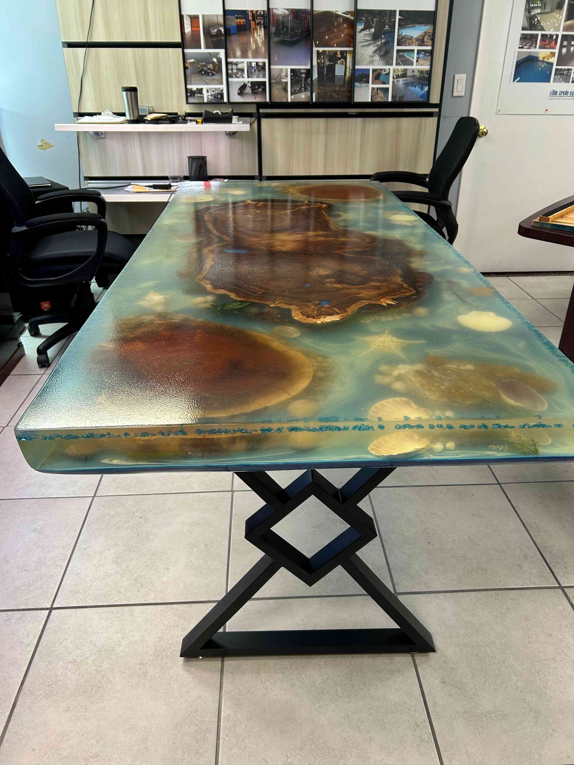 Resin table with abstract designs, set in an office space, with black metal base.