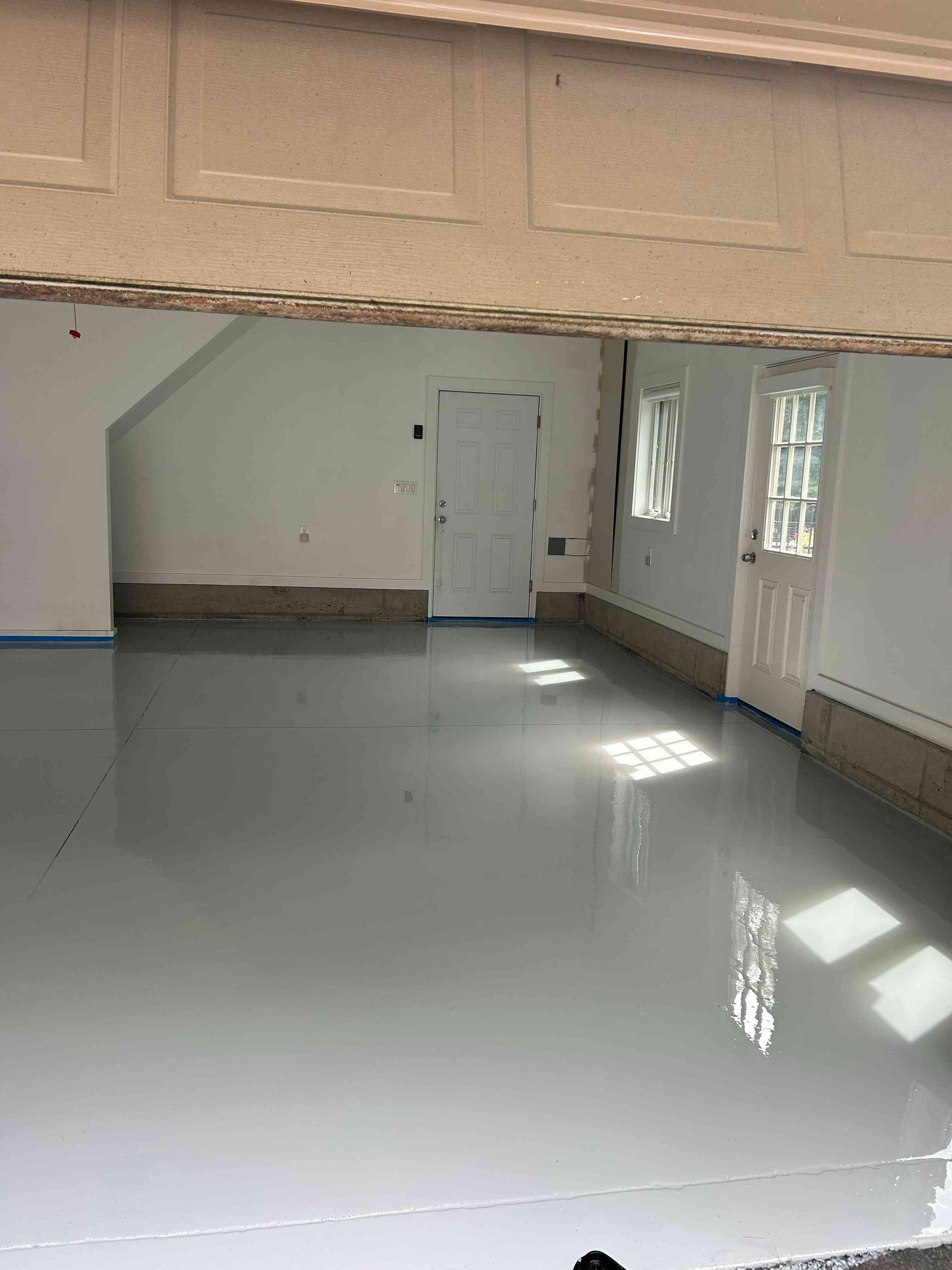 Empty garage with light gray epoxy floor and white walls.