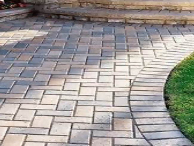 Brick patio with curved border adjacent to grass and steps.