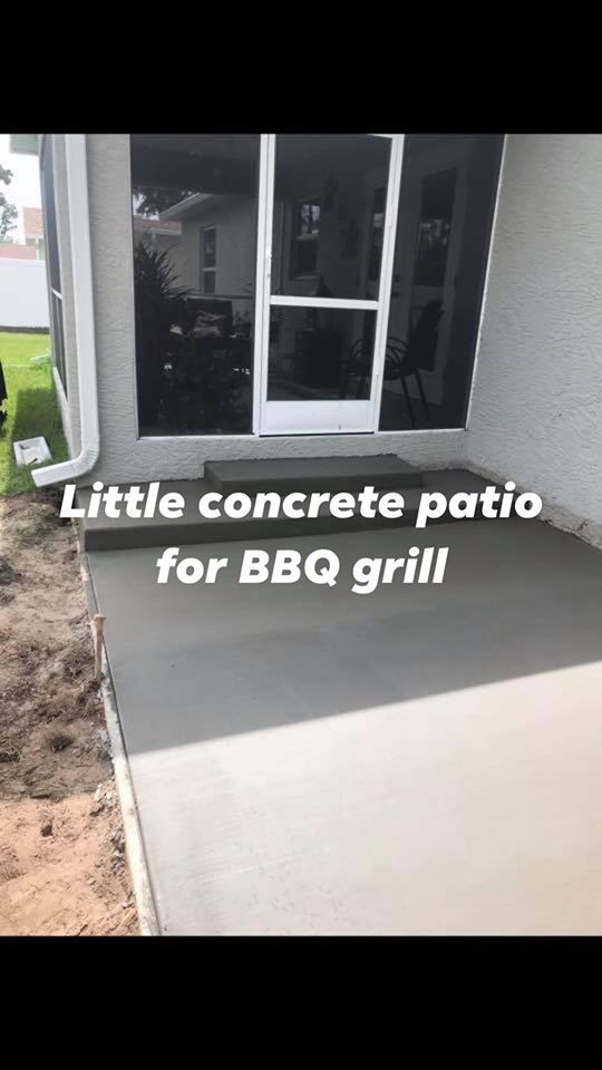 Newly poured concrete patio next to a house with steps leading to a door; meant for a BBQ grill.