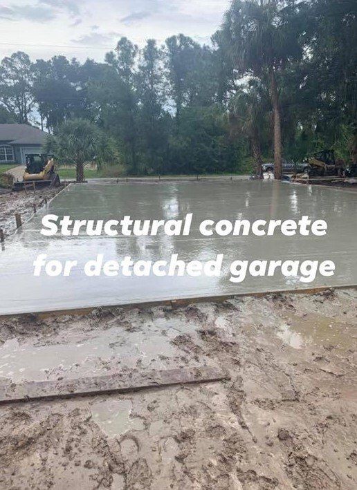 Newly poured structural concrete foundation for a detached garage, surrounded by mud.