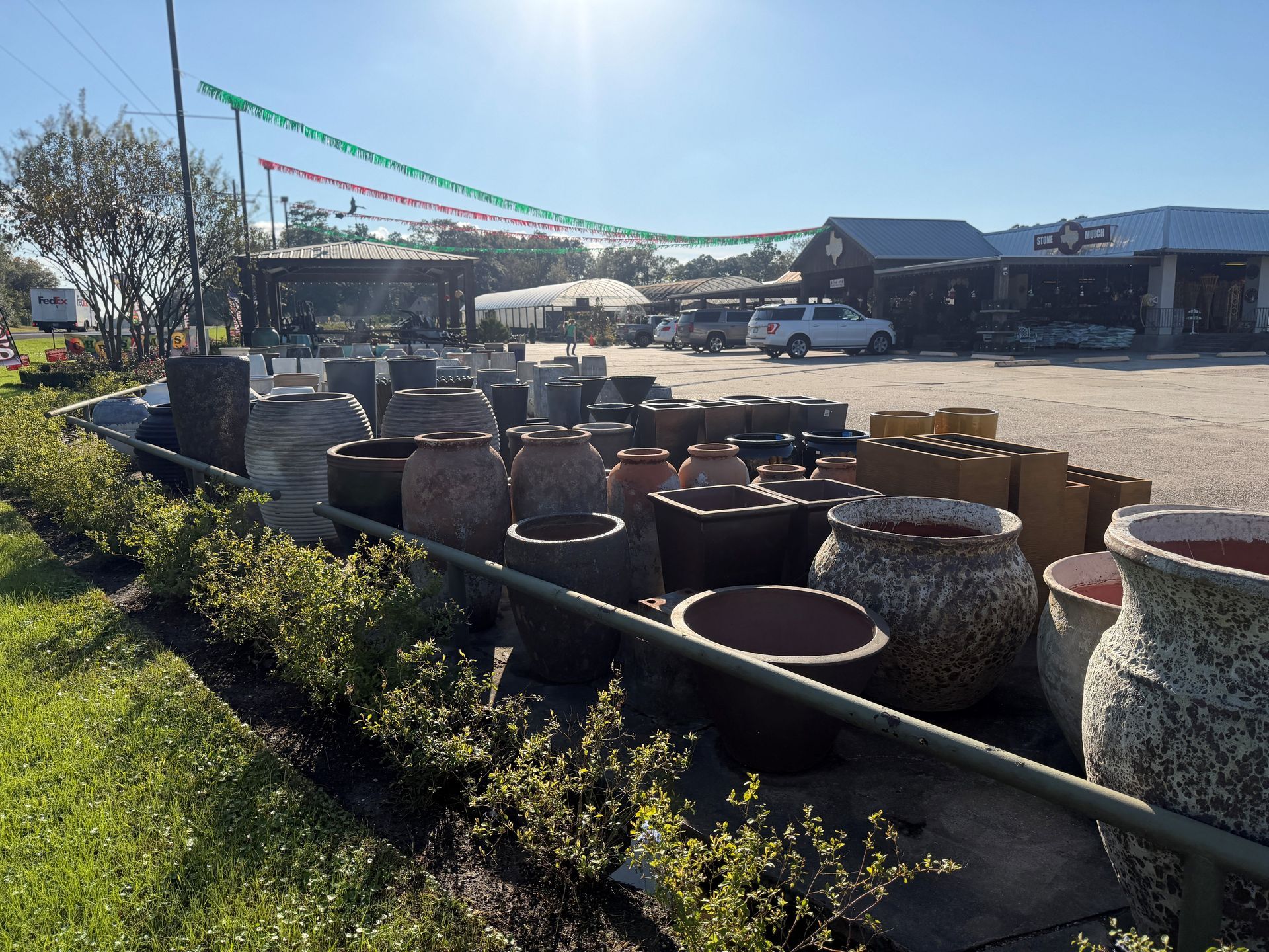 Outdoor display of various garden pots for sale at a nursery.